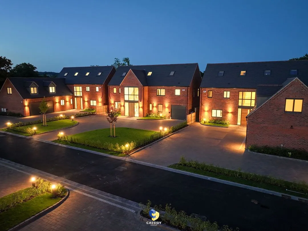 Night view of modern brick houses with illuminated windows, doors, and outdoor lighting.