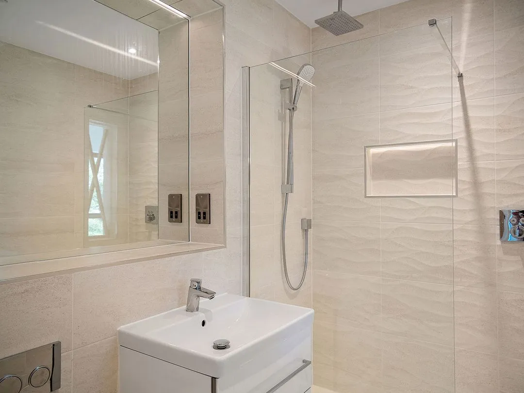 Modern bathroom with white sink, large mirror, and walk-in shower with rain showerhead and hand shower.
