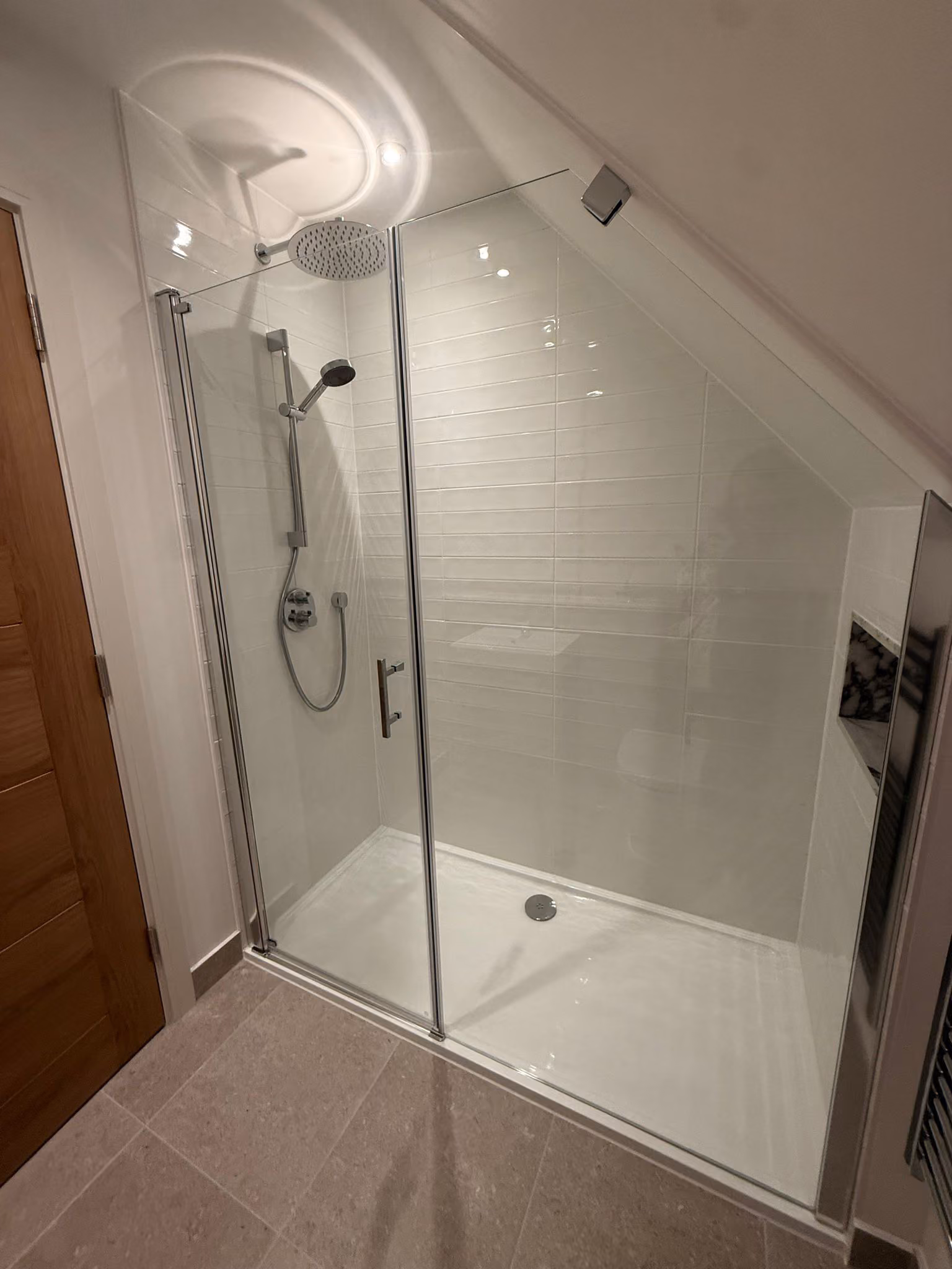 Modern bathroom shower with glass sliding door, overhead rain showerhead, and hand shower.