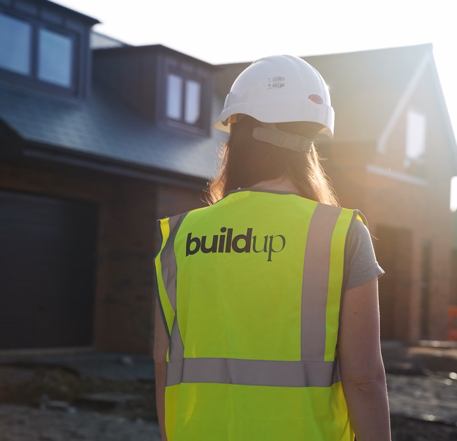 Rosey Cassidy wearing a white hard hat and high-visibility vest labeled 'buildup' at a construction site.